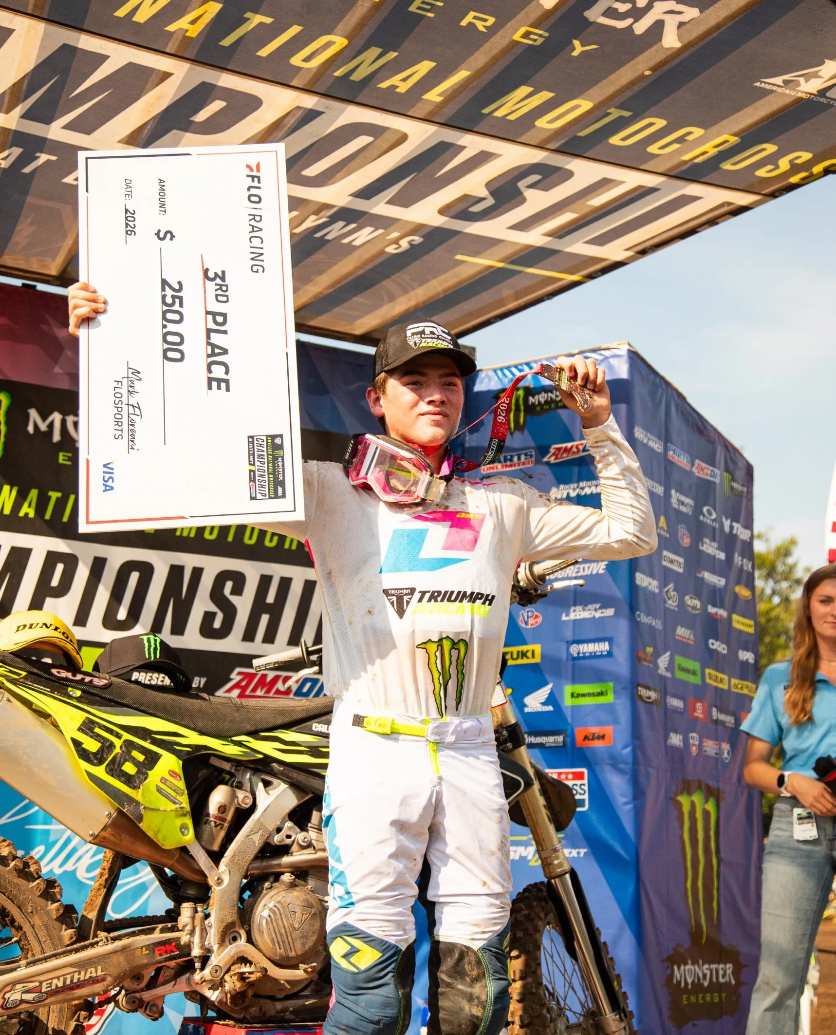 A PRC rider on the Loretta Lynn's 2026 podium holding a 3rd place check
